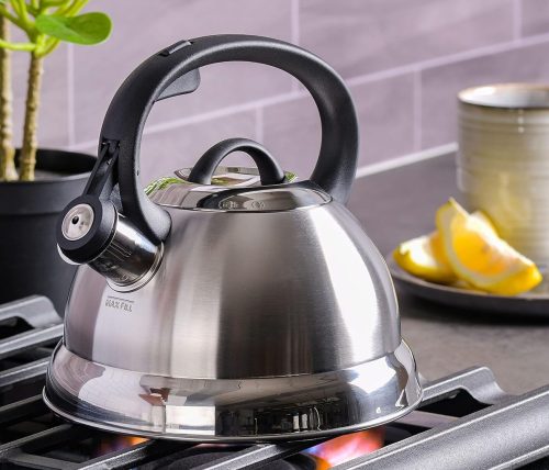 A whistling tea kettle placed on the fire stove.